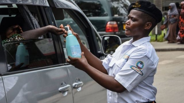 Oficial de segurança distribui líquido de higienização das mãos a um passageiro