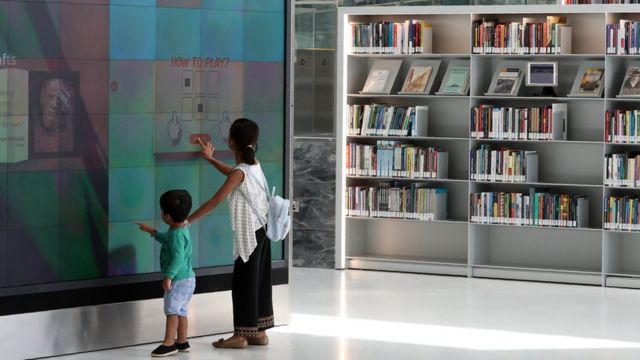 طفلة وطفل يتصفحان لوحة رقمية في المكتبة