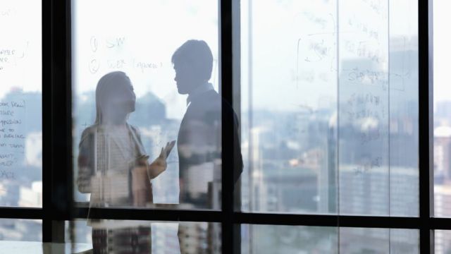 Silhouette of two business people talking in office