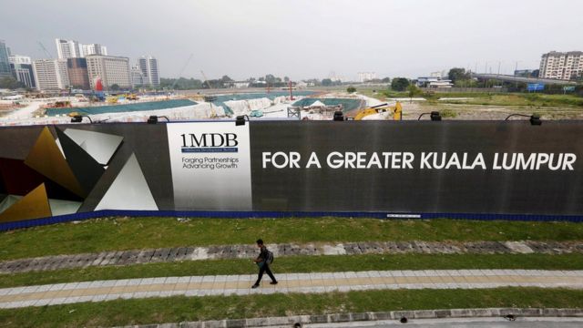 A man walks past a 1MDB billboard at the fund's flagship Tun Razak Exchange development in Kuala Lumpur, 1 March 2015.