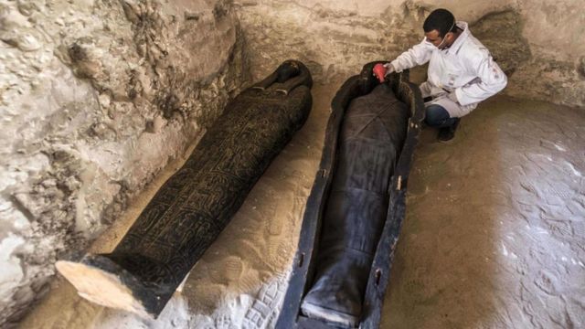 Археолог осматривает мумии в некрополе Эль-Ассасиф в Египте