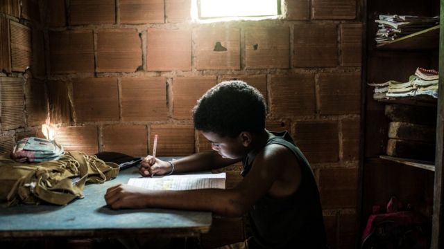 Un niño en una casa precaria haciendo tarea.