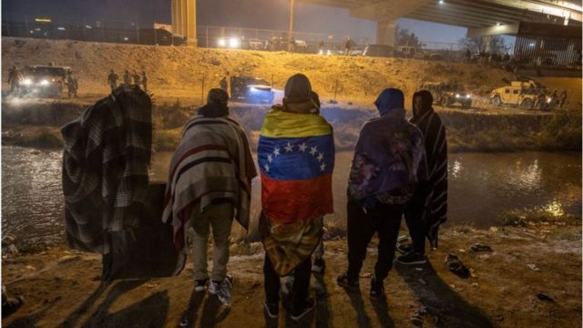 Pessoas em grupo, uma delas com bandeira da Venezuela