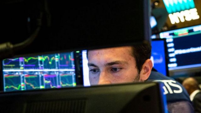 Homem olhando gráficos econômicos em tela de computador