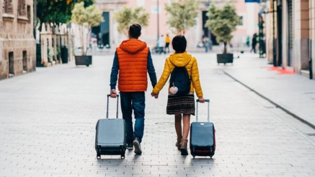 Una pareja caminando en la calle con maletas