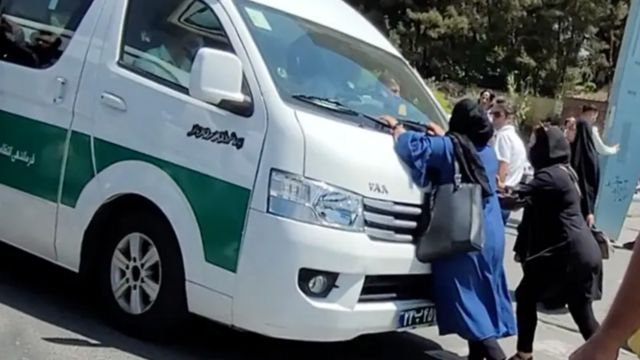 ون گشت ارشاد در حال حمل زنان بازداشتی است و دو زن جلوی ماشین مانع حرکت آن شده‌اند 