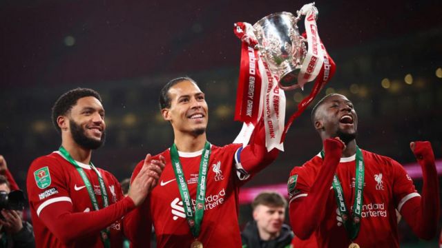 Virgil van Dijk of Liverpool holds the trophy as he celebrates with Joe Gomez and Ibrahima Konate