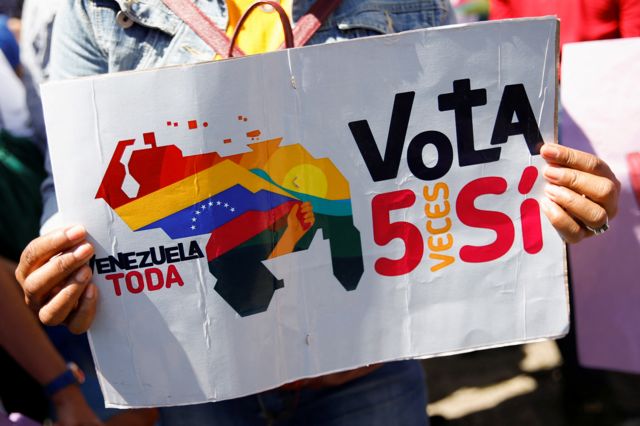 Un venezolano sostiene una pancarta que dice: “Venezuela toda, vota SÍ 5 veces”.