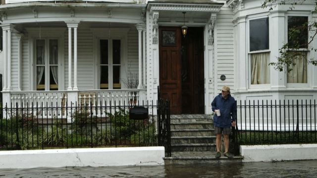 Un residente observa la acerca inundada mientras está de pie en el borde de la escalera en Charleston, el 8 de octubre el año 2016