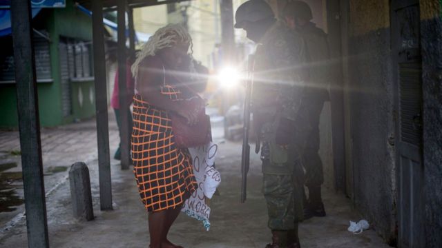 Soldados revistam uma mulher na entrada da comunidade Cidade de Deus