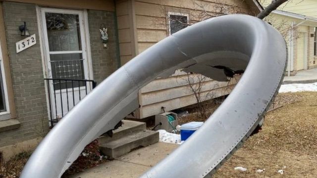 Wreckage of what appears to be an airplane tire in front of a house