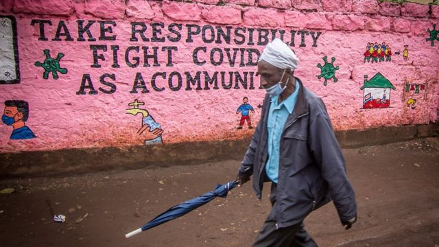 Un homme portant un masque facial par précaution, passe devant un mur avec un graffiti de sensibilisation pendant la pandémie du virus corona.