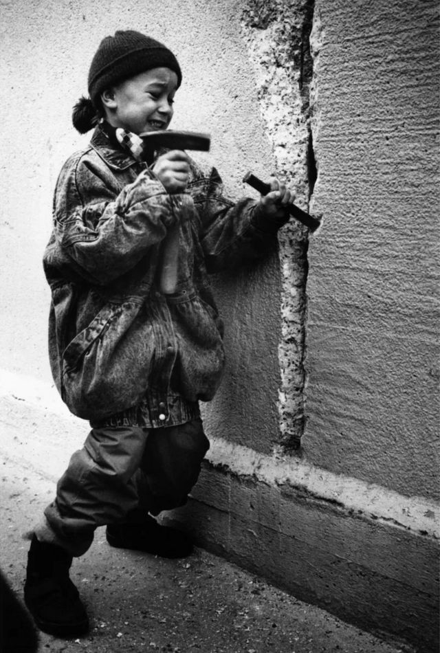 A woman tries to break down a German wall