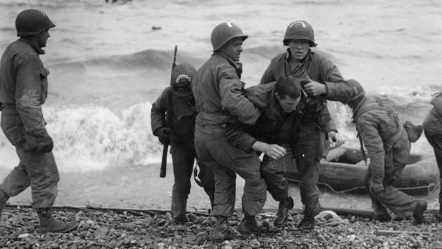Médicos de EE.UU. ayudan a un soldado en la llegada a Normandía, Francia, en la Segunda Guerra Mundial.