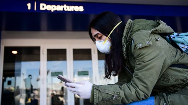 A passenger wearing a protective face mask, amid concerns about the COVID-19 outbreak, looks at her phone in Linate Airport in Milan, after millions of people were placed under forced quarantine in northern Italy as the government approved drastic measures in an attempt to halt the spread of the deadly coronavirus that is sweeping the globe.