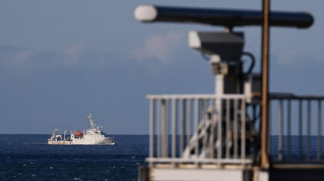 Sebuah kapal laut bermanuver melewati menara radar saat berlayar menjauhi lokasi di mana militer China diyakini melakukan latihan tembakan langsung.