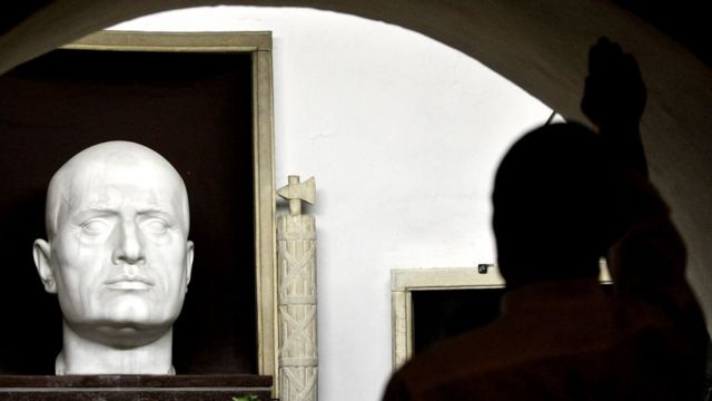 A far-right support makes the fascist salute by Mussolini's tomb in Predappio