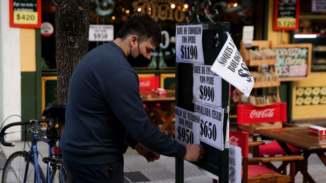 Una persona colocando carteles de precios fuera de un restaurante