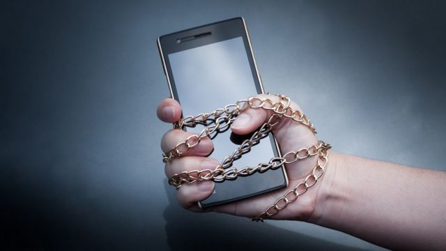 Mano encadenada a un celular