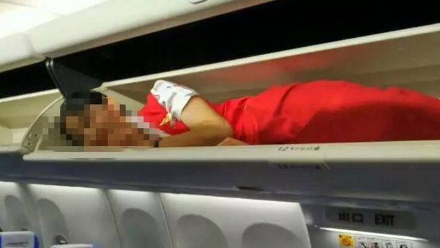 This photo seen on the WeChat account of the 'Civil Aviation Tabloid' channel, shows an air stewardess lying in an overhead luggage compartment