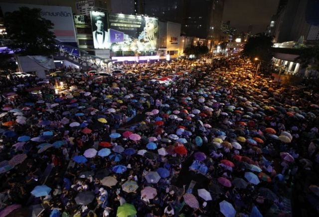 Pro-democracy protesters with umbrellas to protect themselves from the rain attend an anti-government protest at intersection on the main road in Bangkok, Thailand, 16 October 2020.