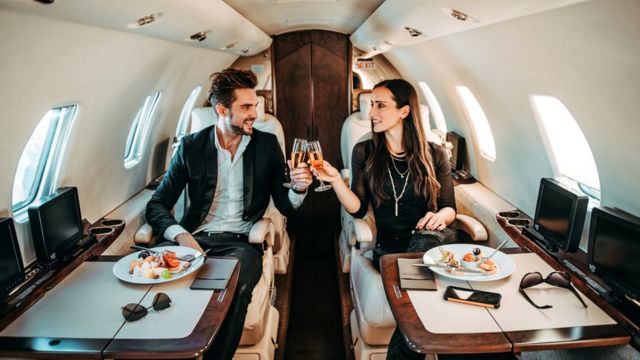 Casal brindando com champanhe em avião particular