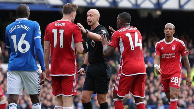 Referee Anthony Taylor is confronted by Chris Wood and Callum Hudson-Odoi of Nottingham Forest