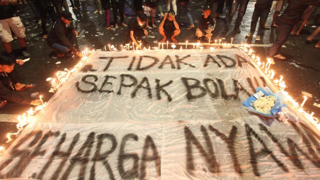 Suporter Persebaya menyalakan lilin saat mengikuti doa bersama di Tugu Pahlawan, Surabaya, Jawa Timur, Senin (3/10/2022).