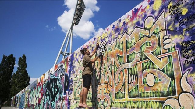 رجل يرسم على جدار برلين
