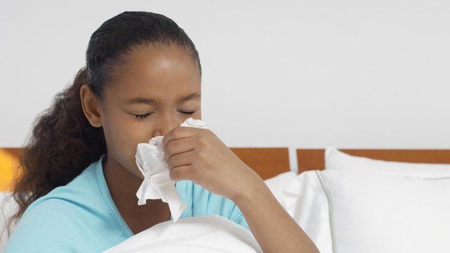 girl sneezing in hospital bed