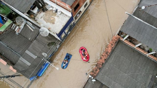 Foto aérea mostra rio inundando e botes resgatando pessoas
