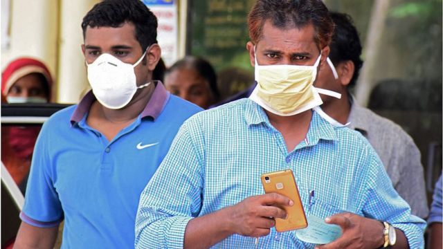 నిపా వైరస్ బారిన పడకుండా ముక్కుకు మాస్కులు ధరించిన వ్యక్తులు