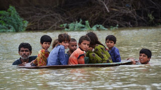 Una antena parabólica se utiliza para trasladar a los niños a través de una zona inundada tras las fuertes lluvias monzónicas en el distrito de Jafarabad, provincia de Baluchistán