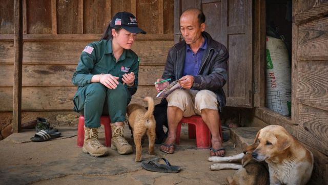El agricultor Youa Thaiyang explicándole al enlace local de MAG sobre el explosivo que halló en sus tierras.