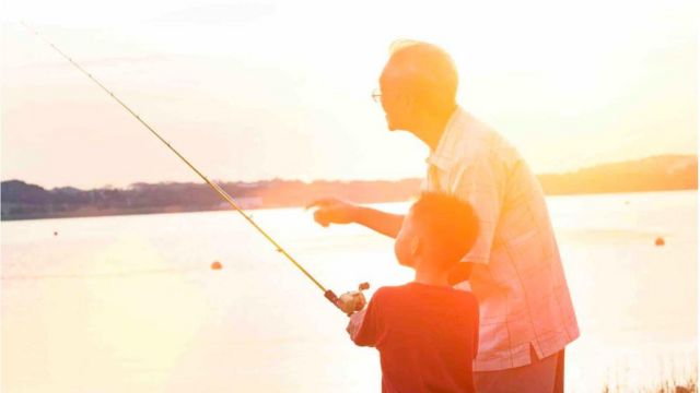 A boy fishing with his grandfather.