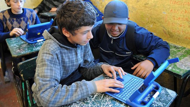Dos adolescentes trabajan con una computadora.