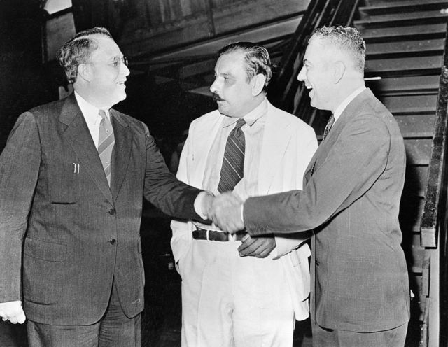 Rexford Tugwell (right) shakes hands with his predecessor Guy Jacob Swope.  In the middle Luis Muñoz Marín, who at that time was president of the island's Senate.