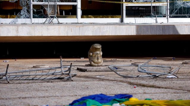 Cabeça de estátua de cabeça para baixo, em meio a destroços em frente ao STF