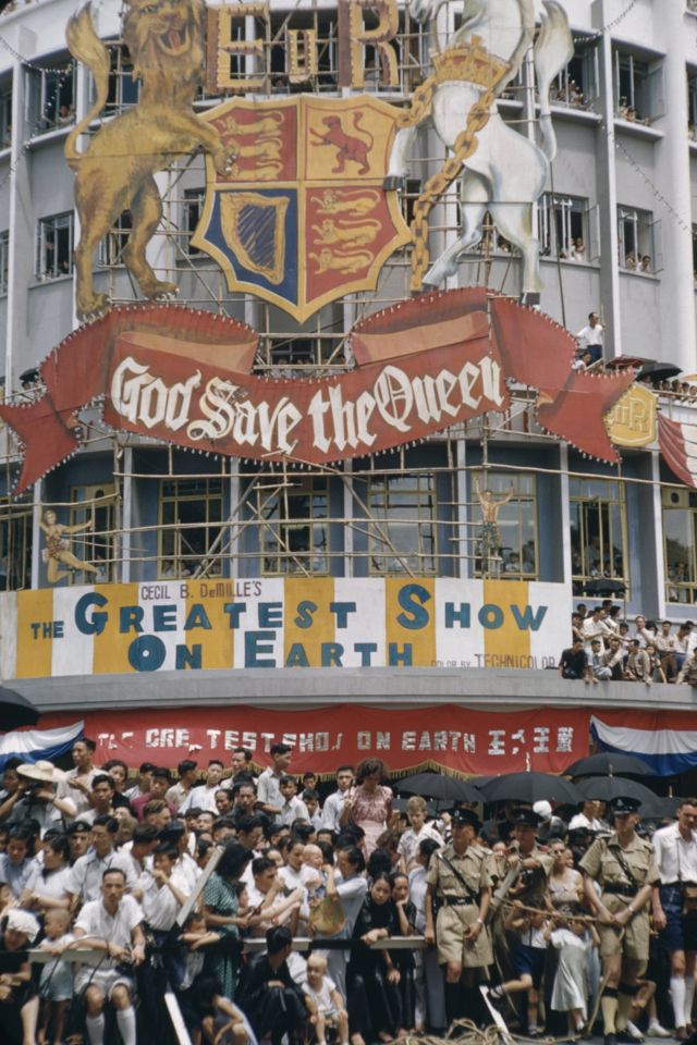 香港九龍旺角彌敦道上市民在「天佑女王」大型牌匾下圍觀慶祝英女王登基巡遊（3/6/1953）