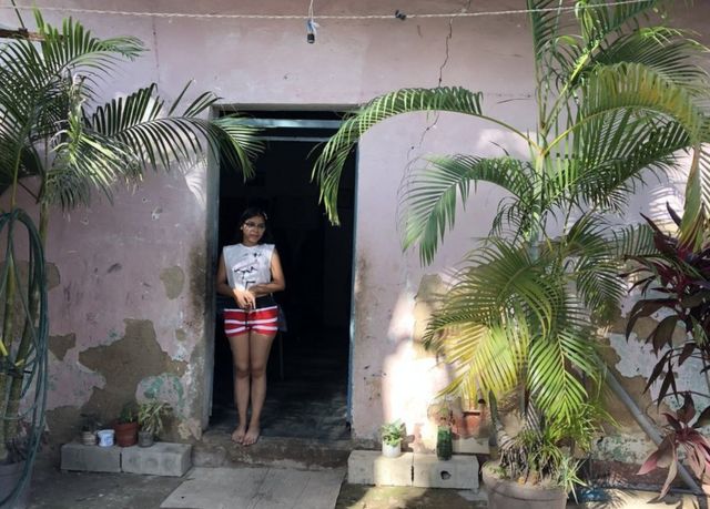 Valeria standing at the door of her home in La Pedrera, Maracay, Venezuela