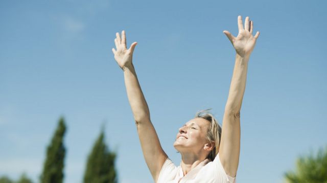 mujer respirando con los brazos en alto