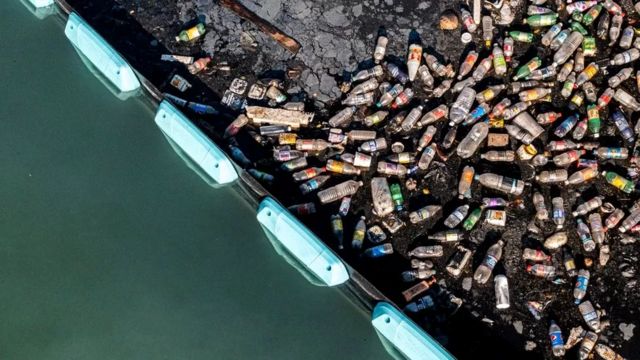 Garrafas de plástico se acumulam atrás da barreira Interceptor da Ocean Cleanup em Kingston Harbour, Jamaica