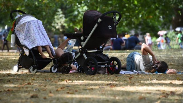 Una familia descansa a la sombra en un parque de Londres.