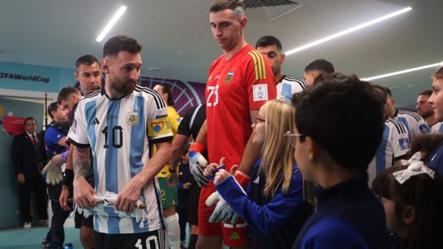 Lionel Messi speaks to children as they prepare to walk out of the tunnel