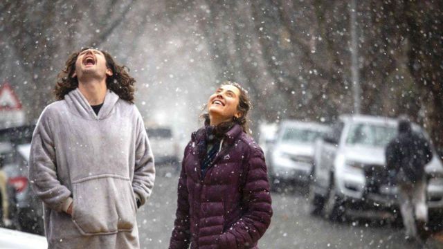 Двое людей смотрят на падающий снег