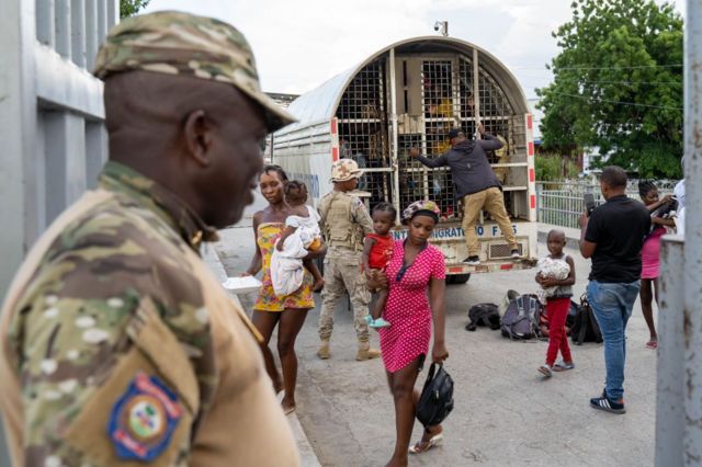 Inmigrates haitianos detenidos bajo la atenta mirada de un policía dominicano.