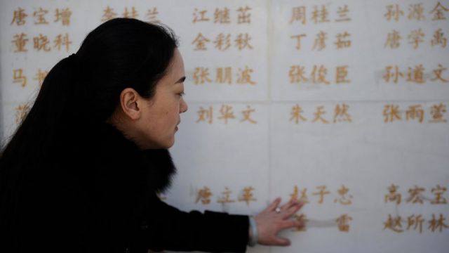 The wife of an organ donor touches her husband's name on a memorial for Chinese organ donors