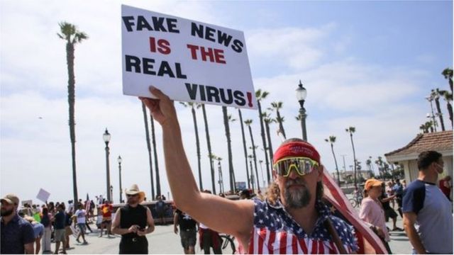 متظاهر يحمل لافتة تشكك في وجود فيروس كورونا في مظاهرة في كاليفورنيا