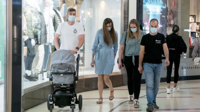 People with masks walk through a shopping center in Spain