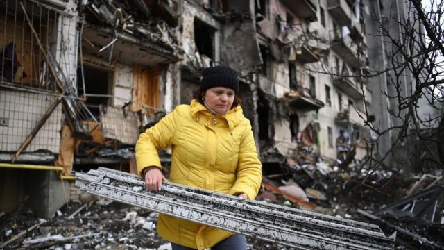 Woman in Kiev clearing rubble after a shelling.